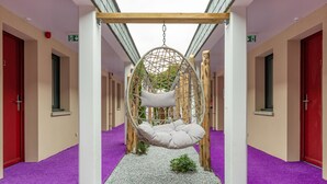 A hallway with a hanging swing chair, red doors, and purple carpet. - Brit Hotel Au Pays de Vitre (Etrelles)