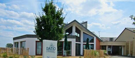 A modern building with a sign for Le Patio Restaurant and Brit Hotel.
