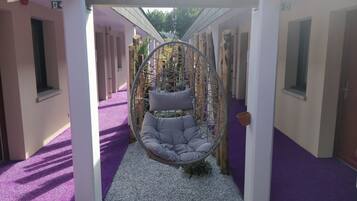 A hanging chair in a corridor with purple carpeting and white walls.