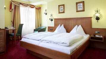 Habitación de hotel con una cama grande, un escritorio con silla, cómoda y dos lámparas de pared.