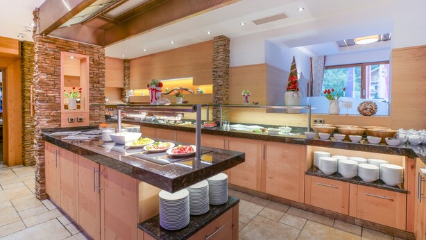 A modern kitchen with a granite countertop, stone accents, and a Christmas tree decoration. - Hotel Untersberg (Groedig)