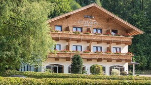 A wooden chalet with balconies, surrounded by lush greenery. - Hotel Untersberg (Groedig)