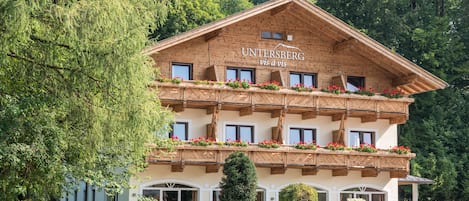 A wooden chalet with balconies, surrounded by lush greenery.