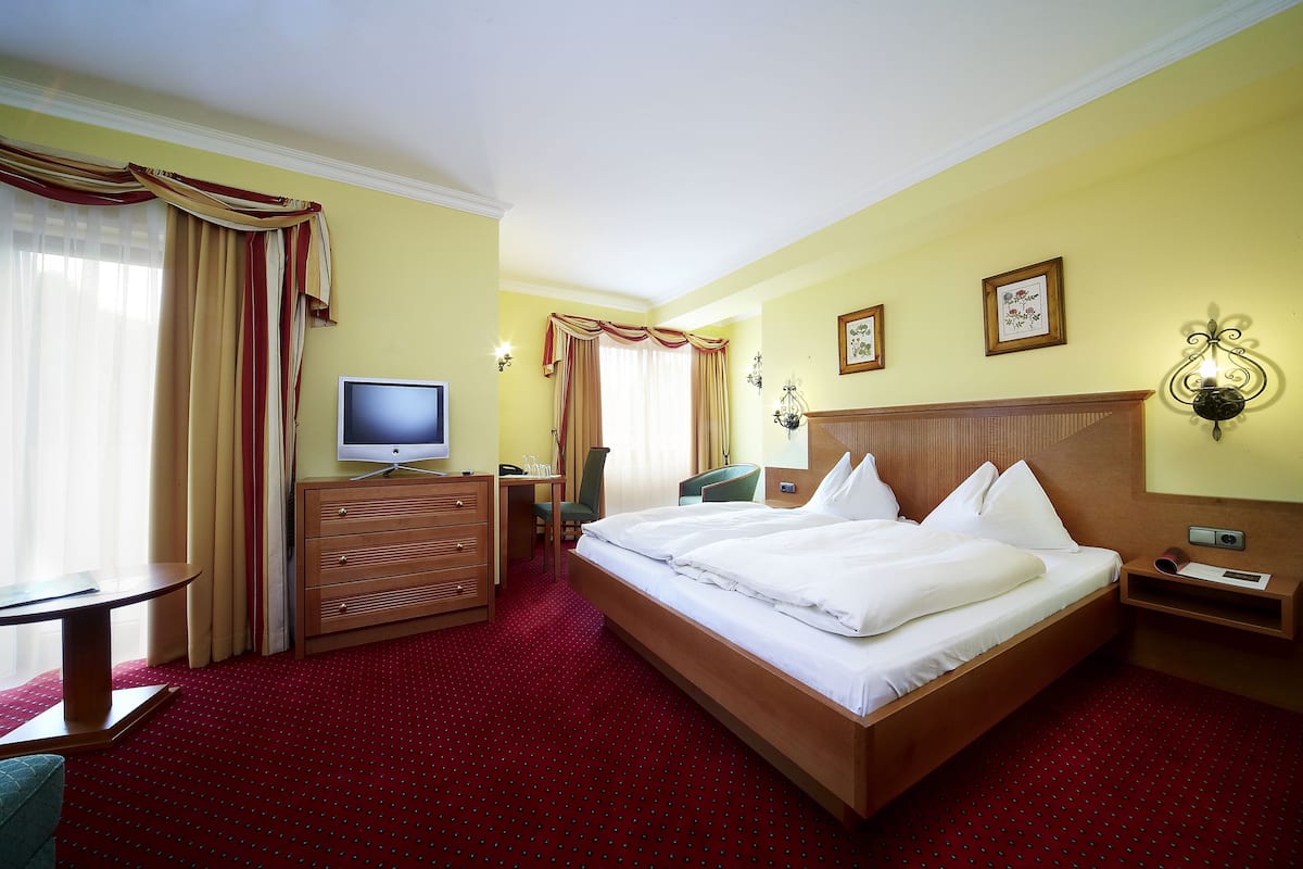 A hotel room with a large bed, a desk with a computer, a television, and a small table.