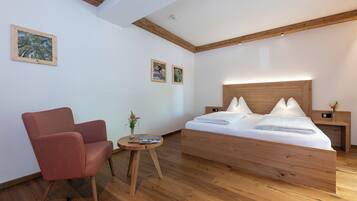 Un dormitorio moderno con una cama de madera, un sillón rojo y una mesita redonda con un florero.