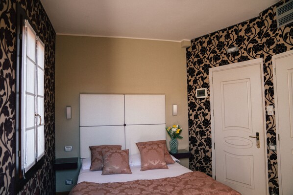 Une chambre d’hôtel avec un lit, une table de chevet, un vase de fleurs et une porte.