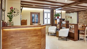 A reception area with a wooden reception desk, white chairs, a bookshelf, and a clock on the wall. - Mapoula (Santiago de Compostela)
