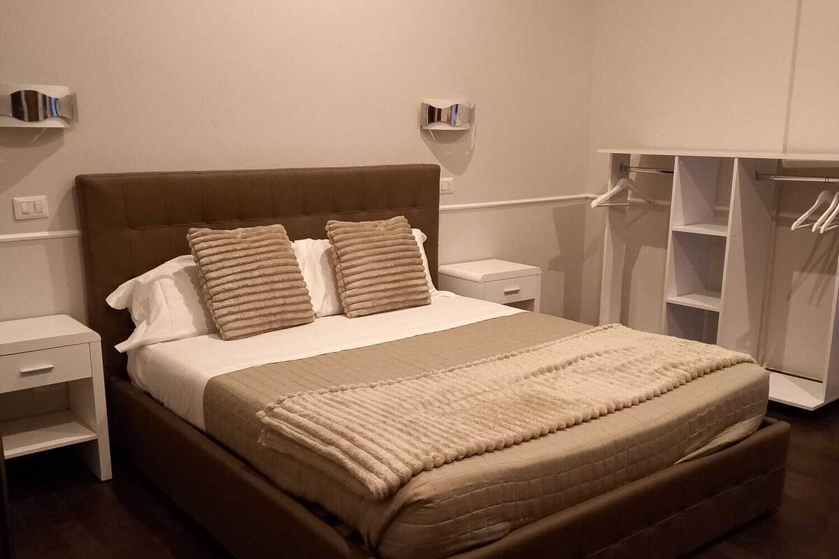 Quarto com uma cama grande, uma mesa de cabeceira e um guarda-roupa.