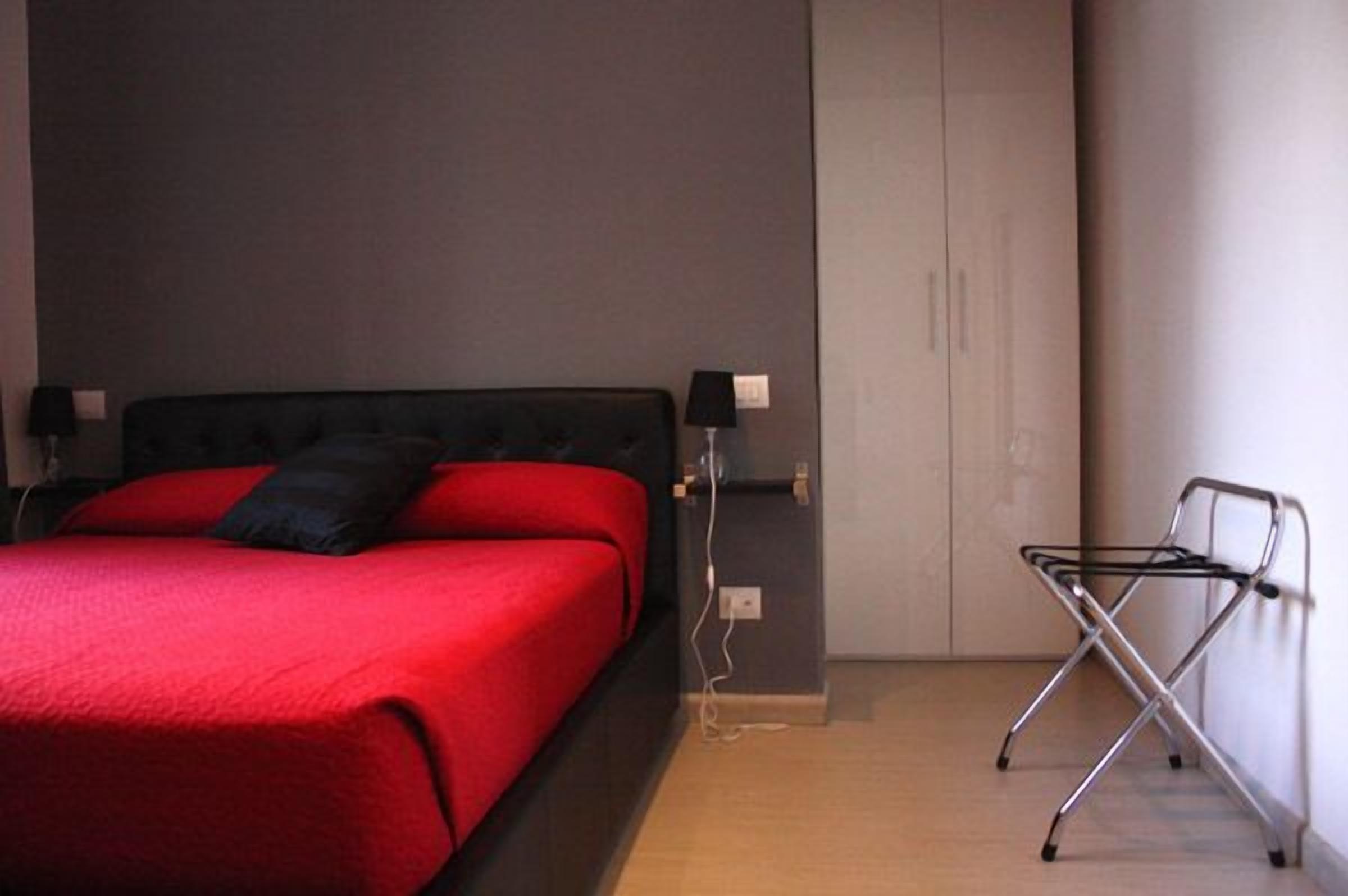 Une chambre à coucher avec un lit, des lampes de chevet, une armoire et une chaise pliante.