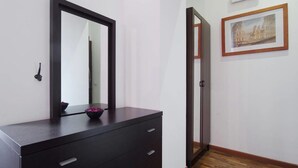 Ein Zimmer mit einem dunklen Holzkasten, einem großen Spiegel und einem gerahmten Bild an der Wand.