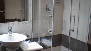Ein Badezimmer mit Duschkabine aus Glas, einem weißen Waschbecken und einem Handtuch.