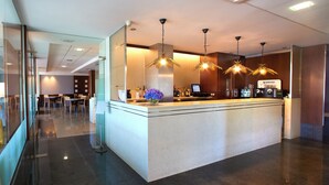 Un moderno vestíbulo de hotel con mostrador de recepción, zona de estar y máquina de café.