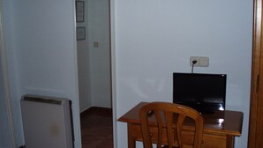 A room with a desk, chair, and a black television. There is a white radiator and a door leading to another room. - Castilla (Madrid)