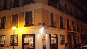 A multi-story building with a ground-floor entrance, large windows, and a visible door. - Castilla (Madrid)