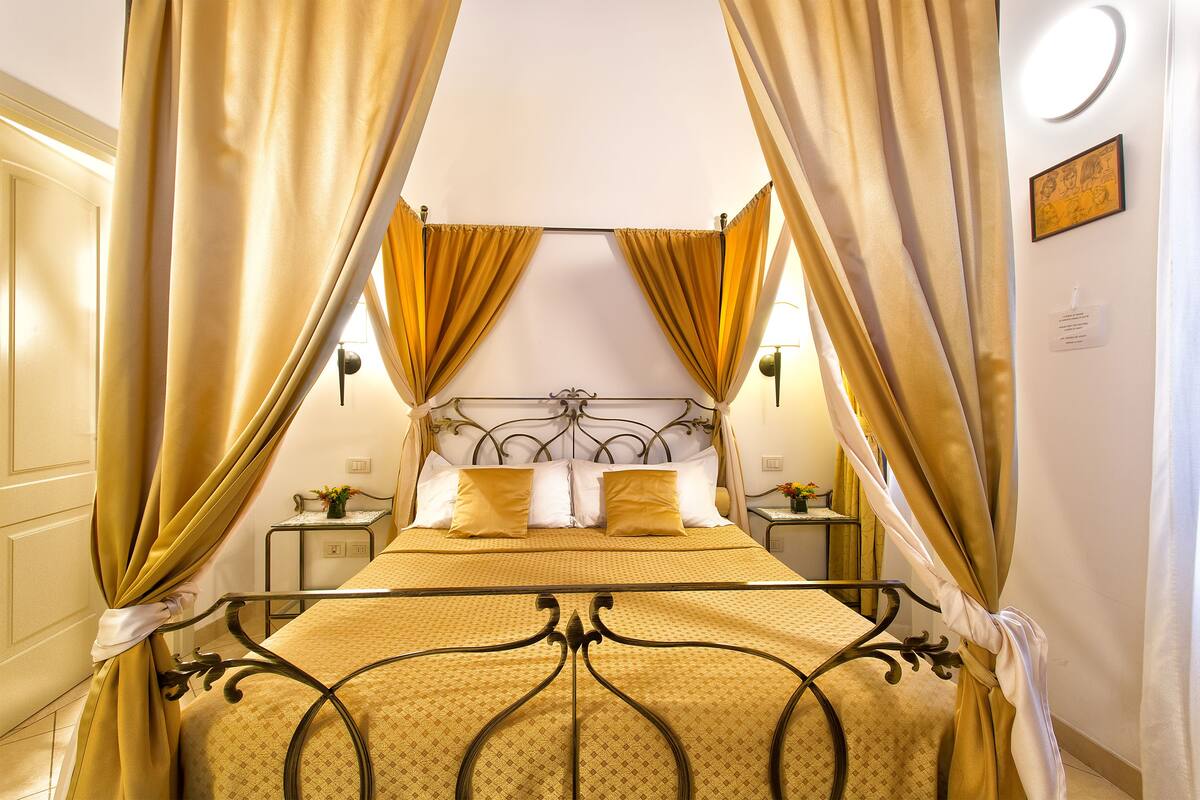A bed with a metal frame, yellow bedding, and curtains.
