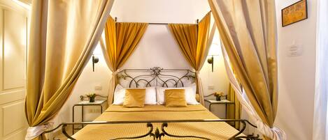 Ein Bett mit Metallgestell, gelber Bettwäsche und Vorhängen.