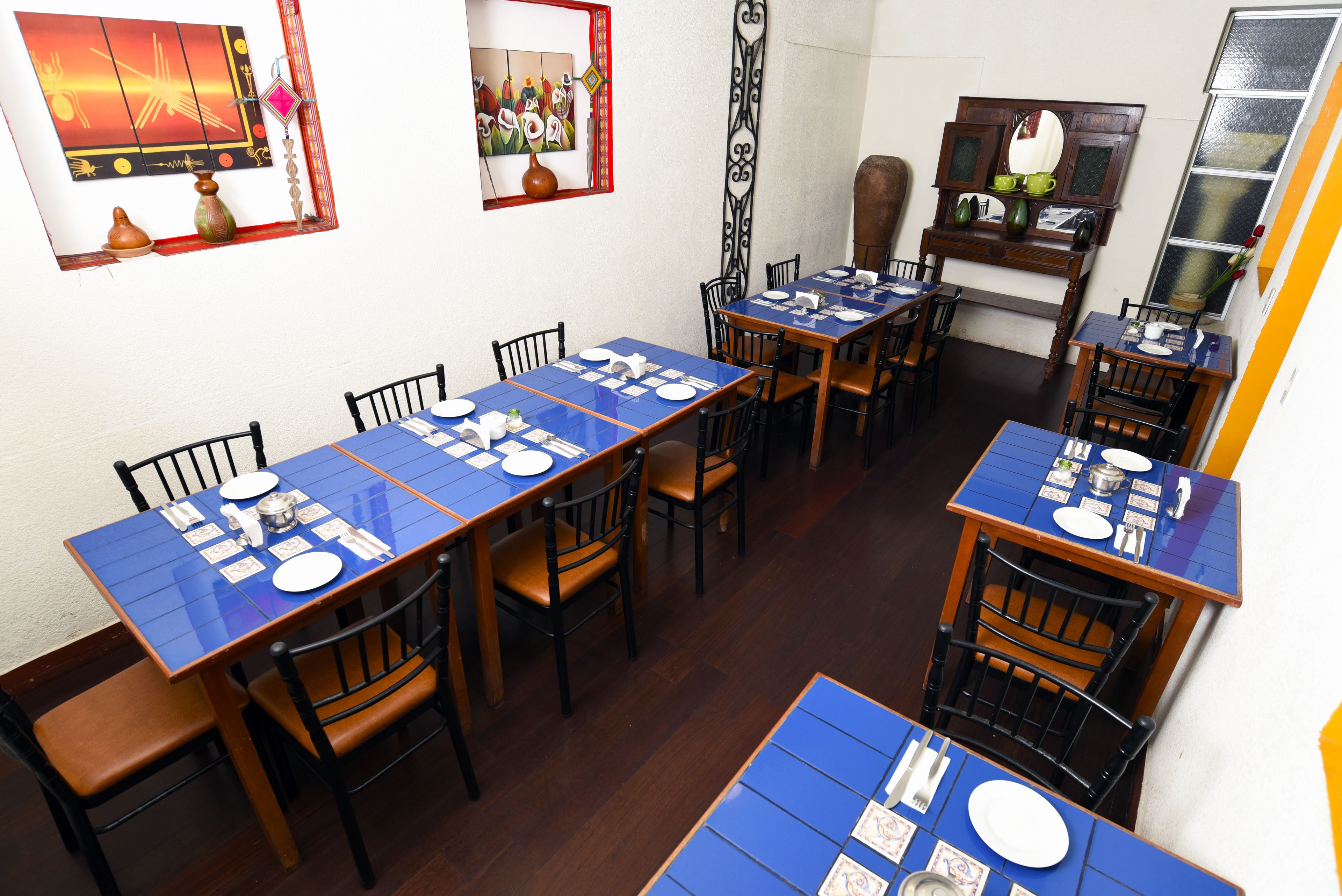 A dining area with multiple tables set for meals, chairs, and decorative wall art.