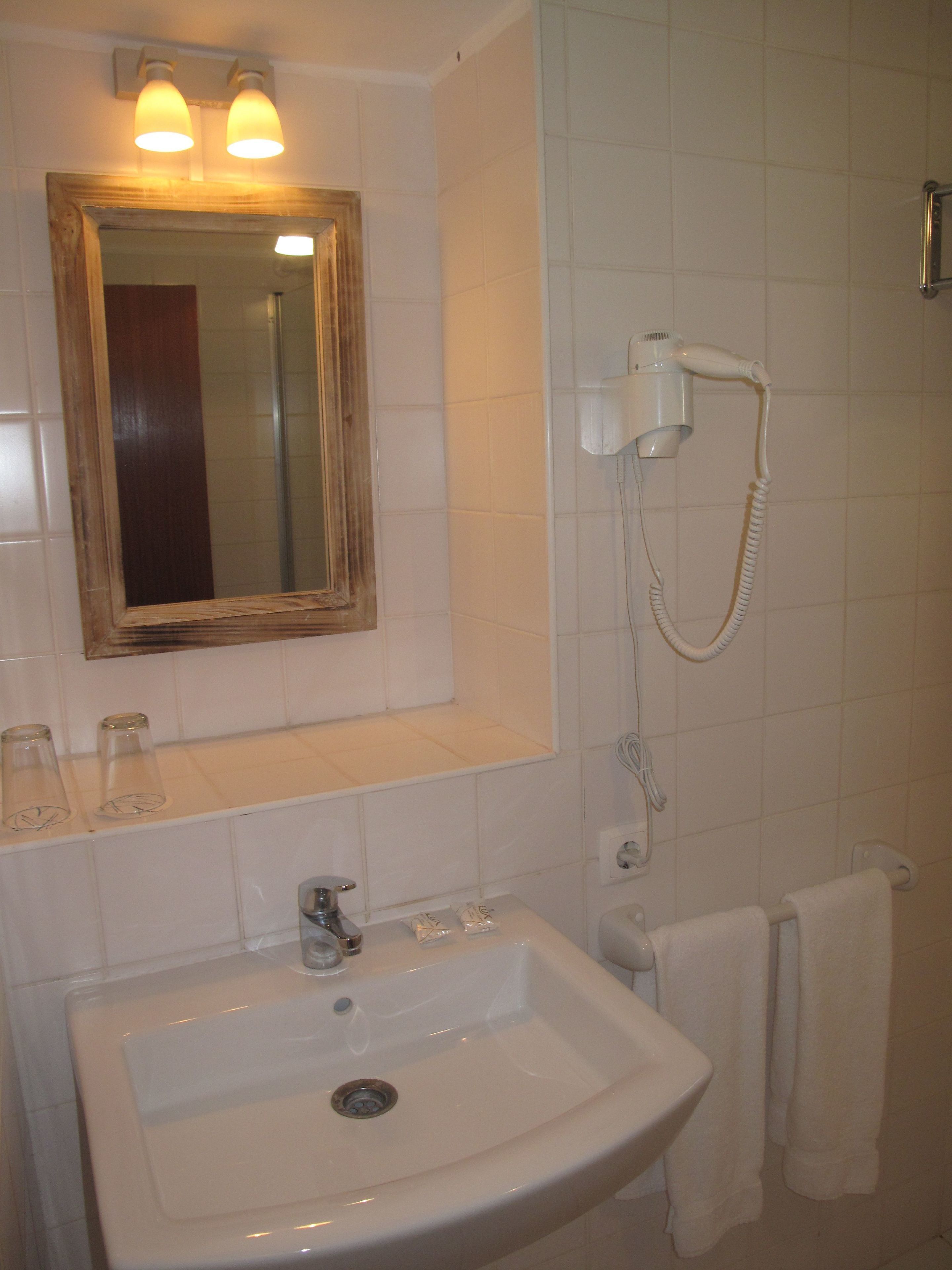 Un baño con lavamanos, espejo y secador de pelo.