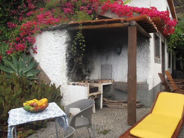 Un área de estar rústica al aire libre con una mesa, sillas y un sillón amarillo.