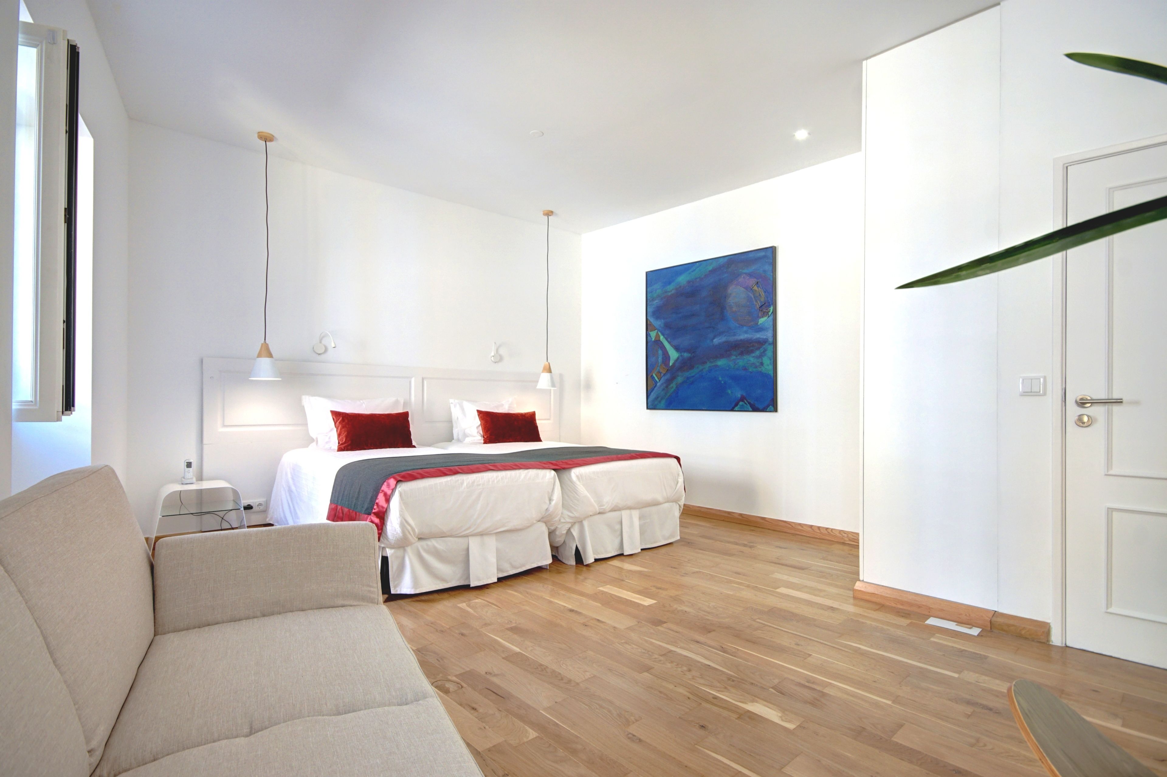 Una habitación de hotel moderna con una cama grande, un sofá, un cuadro en la pared y una puerta.