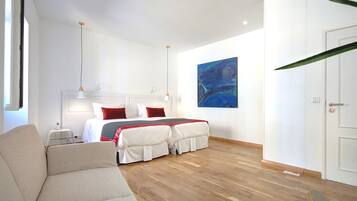 Una habitación de hotel moderna con una cama grande, un sofá, un cuadro en la pared y una puerta.