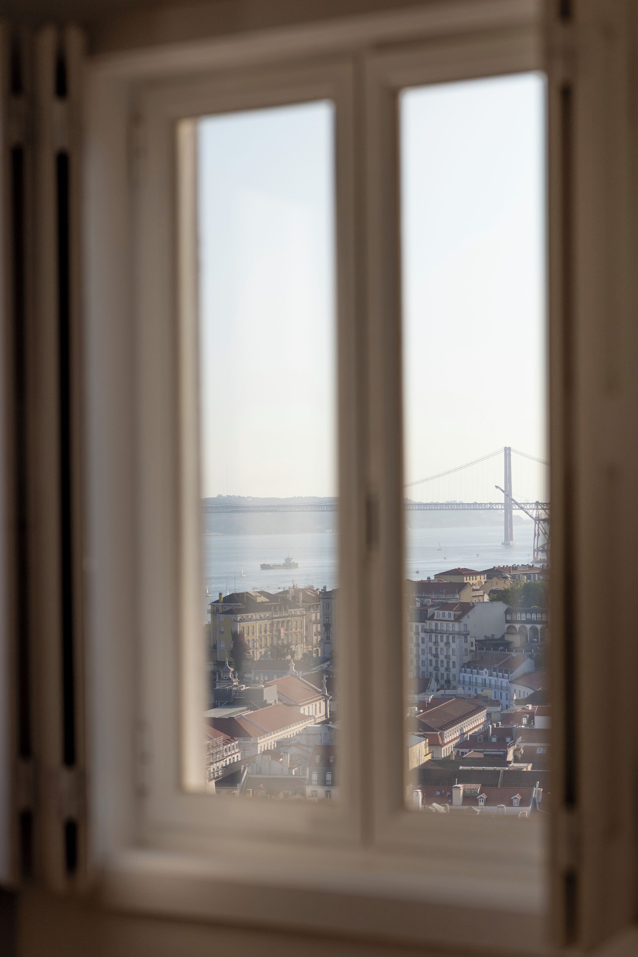 Una vista attraverso una finestra che mostra un panorama urbano con edifici e un ponte.