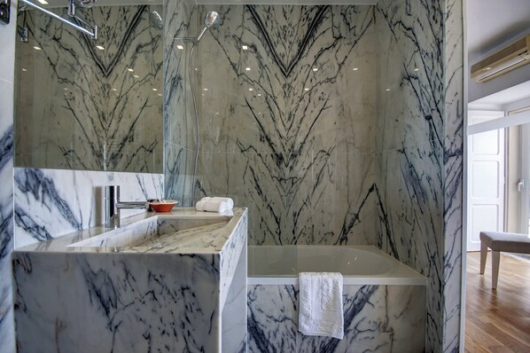 Un baño con paredes de mármol y un espejo grande.
