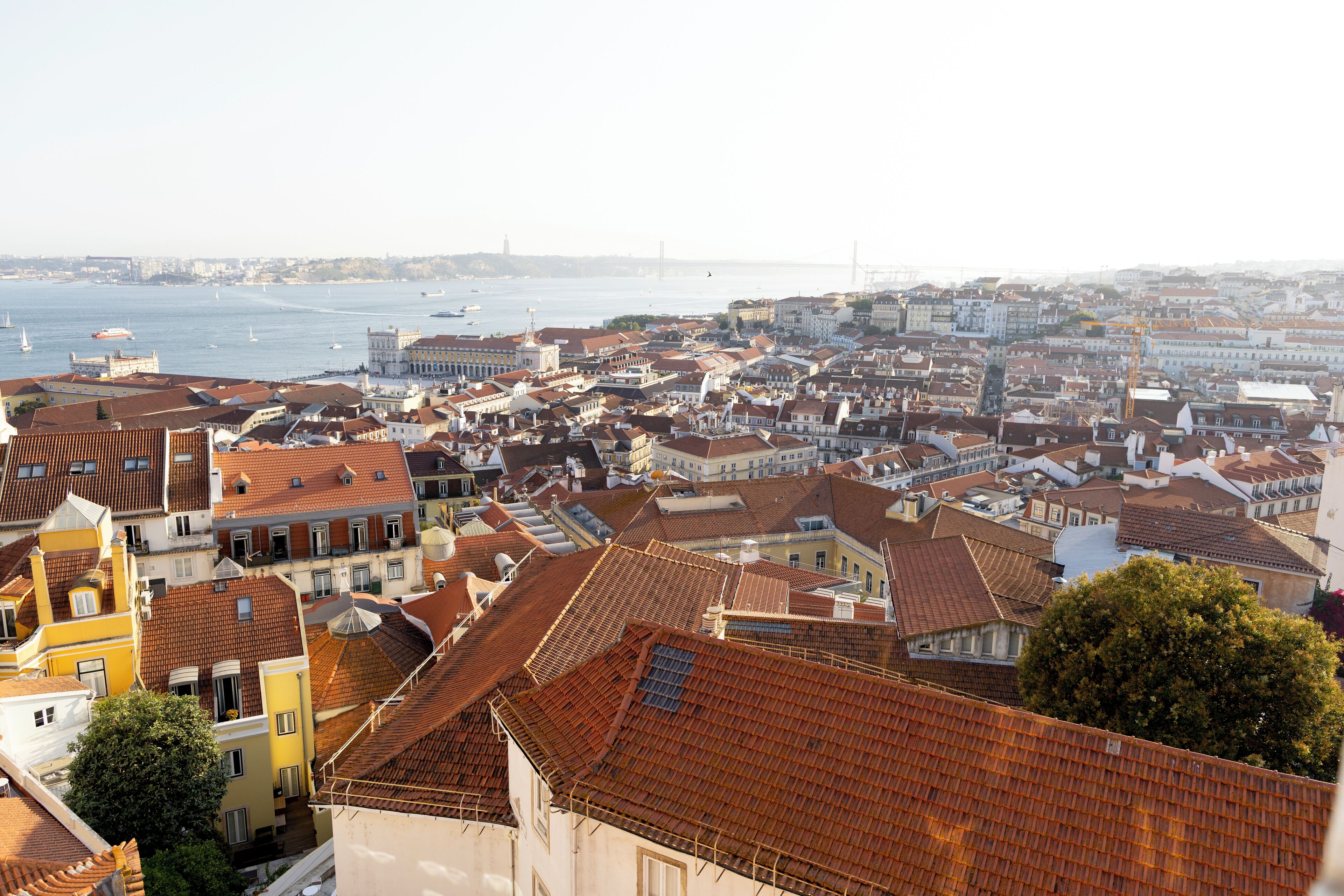 A cityscape with a view of the sea and a bridge in the distance.