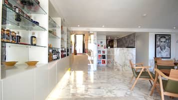 Una cocina moderna con suelo de mármol, repisas de vidrio con utensilios de cocina y sillas de madera.
