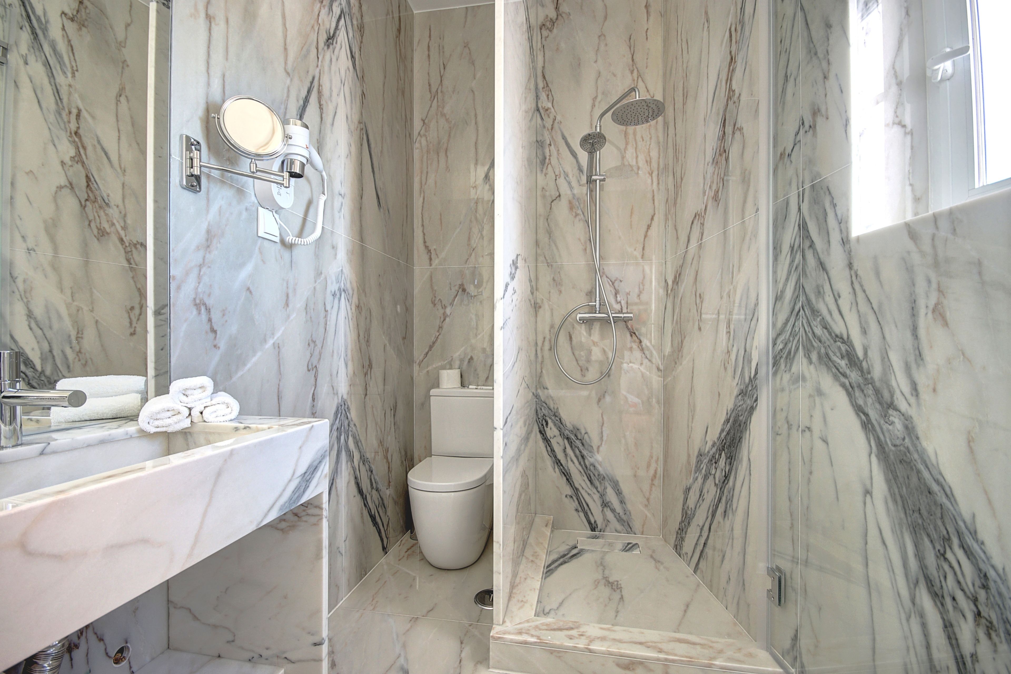 Une salle de bain avec un lavabo en marbre, des toilettes et une douche.