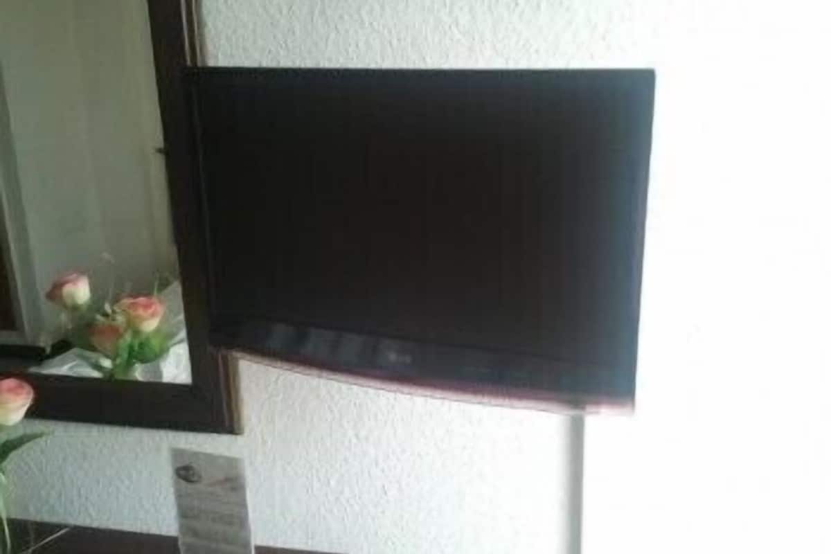 Een kamer met een donkerhouten deur, een witte muur met structuur en een spiegel die een bloemenboeket weerkaatst.