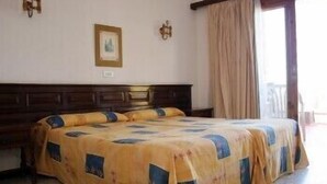 Een slaapkamer met een groot bed, een houten hoofdeinde en een raam met gordijnen.