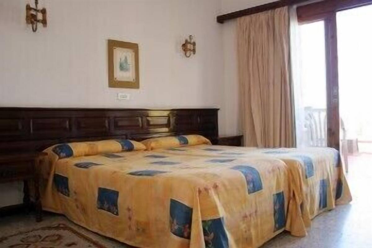 Een slaapkamer met een groot bed, een houten hoofdeinde en een raam met gordijnen.