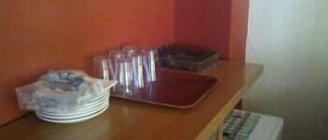 Una encimera de cocina con una pila de platos, una bandeja y un pequeño electrodoméstico.