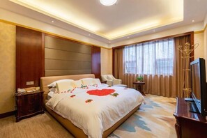 A hotel room with a large bed, bedside tables, a desk, a chair, and a TV. - zhangjiajie Lantian Hotel (Zhangjiajie)