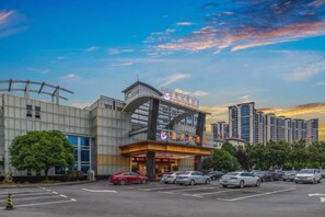 Un hôtel à la façade moderne, doté d’un parking et offrant une vue sur les gratte-ciel en arrière-plan.