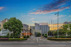 Ein modernes Hotel mit Glasfassade, Parkplatz und blauem Himmel.