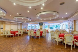 Un salón de banquetes con mesas redondas, sillas y piso de madera.