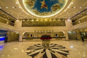 A spacious lobby with a central reception desk, a large floral arrangement, and a ceiling mural. - zhangjiajie Lantian Hotel (Zhangjiajie)