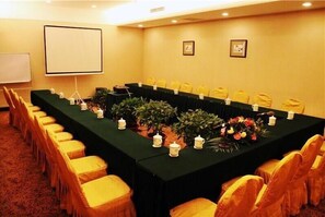 A conference room with a long table, yellow chairs, a projector screen, and framed pictures on the wall. - zhangjiajie Lantian Hotel (Zhangjiajie)