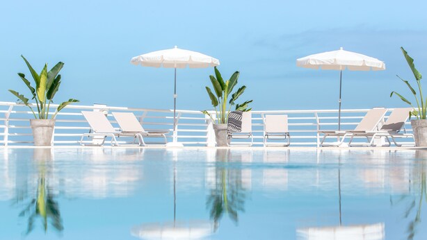 A pool area with lounge chairs and umbrellas, surrounded by potted plants. - Atlantic Holiday Hotel (Adeje)