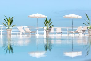 Una piscina al aire libre, sombrillas, tumbonas