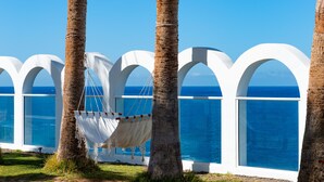 A hammock tied between palm trees, overlooking a pool with clear blue water and white arches. - Atlantic Holiday Hotel (Adeje)
