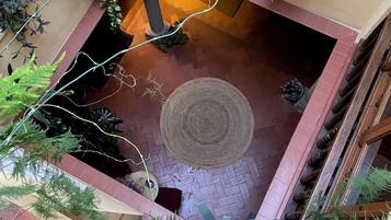 Un patio con plantas en macetas, un tapiz tejido y un banco de madera.
