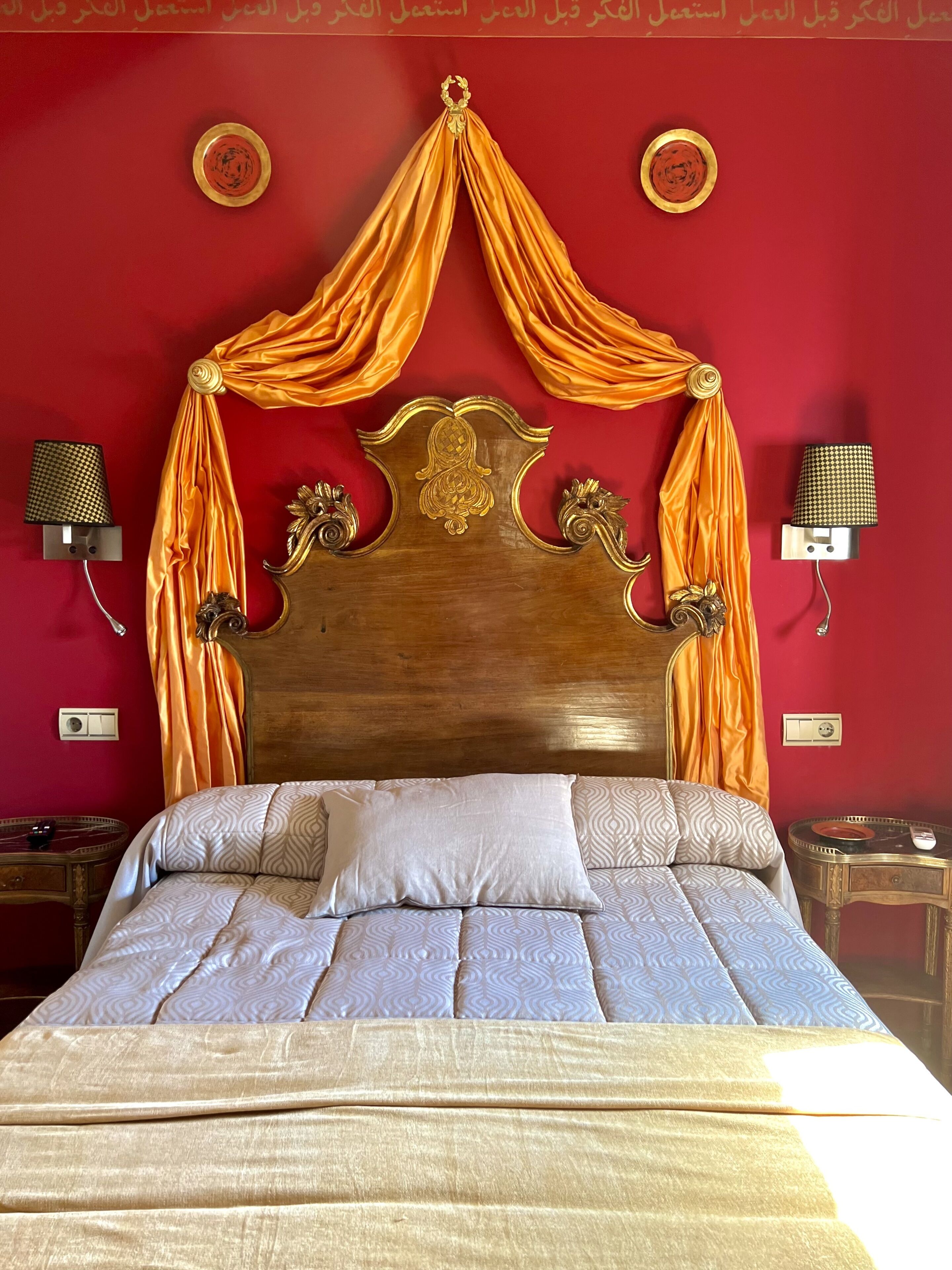 Ein Bett mit Baldachin, einem Holzkopfteil und gemusterten Betttextilien.