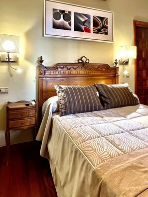 Una cama bien hecha con ropa de cama estampada, un cabecero de madera y dos lámparas de noche.