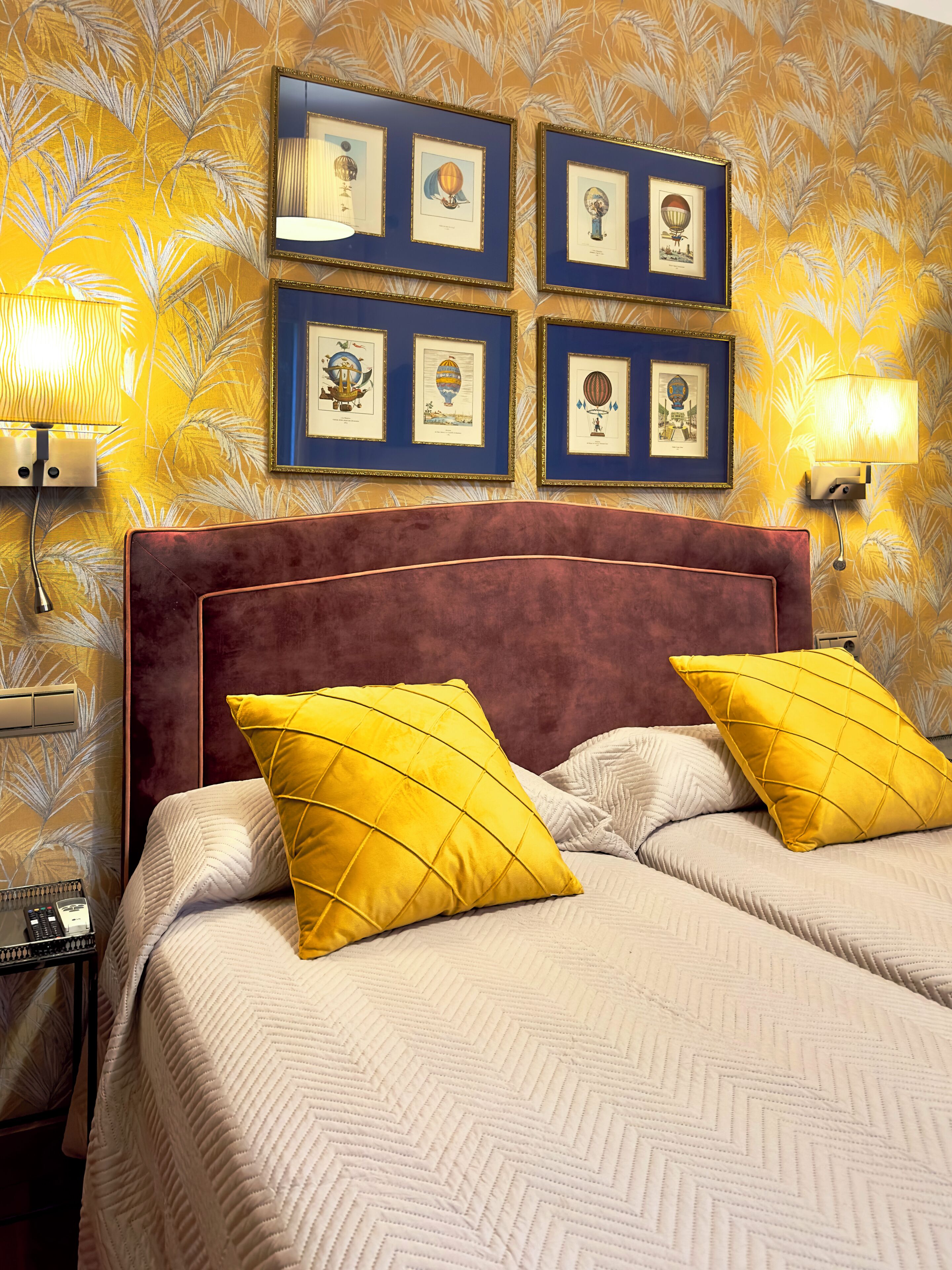 A bed with two pillows, a headboard, and a wall with framed pictures.