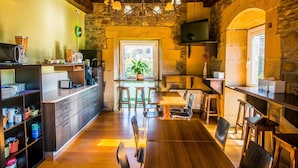 A rustic kitchen with wooden furniture, a stone wall, and a large window. - Hotel Palacio Atxega (Usurbil)