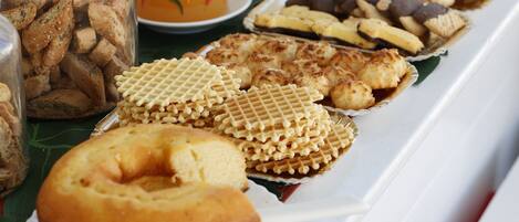 Un buffet de petit-déjeuner proposant une variété de viennoiseries, de biscuits et une sélection de fruits frais.