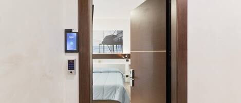 A hotel room with a bed, a digital lock, and a bp4 device on the wall.